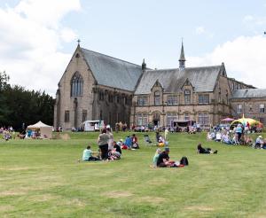 杜伦Ushaw Historic House, Chapels & Gardens的一群人坐在大建筑前面的草上
