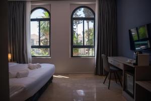 耶路撒冷All Seasons Boutique Hotel - Jerusalem的酒店客房设有一张床、一张书桌和窗户。