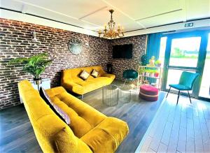 佩罗讷Hôtel Restaurant Kyriad de Péronne的客厅设有黄色沙发和砖墙