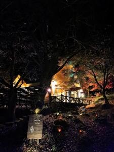 雾岛市星空に包まれる 森の隠れ家　Amrita Lodge ~stay & retreat~的夜晚的房子,前面有标志