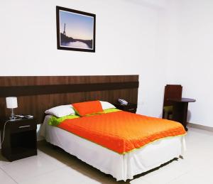 曼塔Manta Airport Hotel的一间卧室配有一张带橙色棉被的床