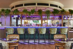 南安普敦Leonardo Royal Southampton Grand Harbour的紫色灯光客房内的酒吧,配有桌椅