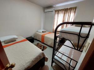 利蒙港Aptos Casa Caribe, habitaciones privadas en aptos compartidos & aptos completos con auto entrada的一间卧室设有两张双层床和一扇窗户。