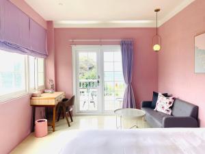 鹅銮鼻垦丁迦南美地-海景花园民宿的粉红色的客房设有一张沙发和一张桌子