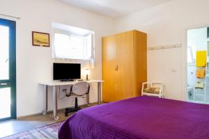 奥尔贝泰洛Casina Orbetello的一间卧室配有紫色的床和一张带电脑的书桌