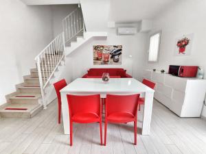 贝瓦尼亚圣彼得Villa Roberta Spiaggiabianca Deluxe - A 20 metri dal mare的一间设有白色桌子和红色椅子的用餐室