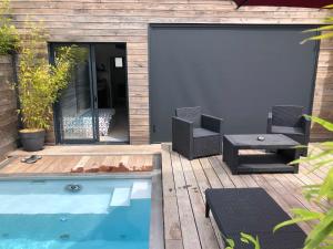 布吕兹Loft privatisé avec spa XXL et piscine chauffée的庭院设有游泳池、两把椅子和一张桌子