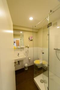 玛特丁恩Gasthof Hotel zum Rebstock的一间带玻璃淋浴、水槽和卫生间的浴室