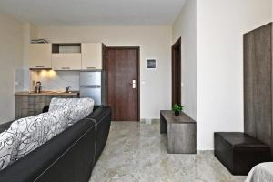 阿菲托斯Sinodinos Deluxe Apartments的一间带黑色沙发的客厅和一间厨房