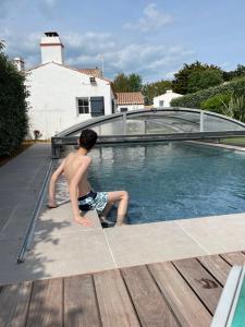 Le Grand VieilChambres d'hôtes LES CHENES VERTS的坐在游泳池边的男孩