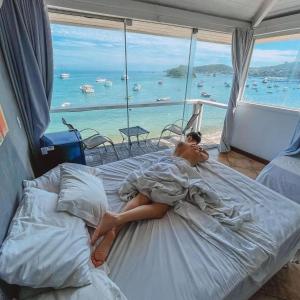 布希奥斯Bamboo Búzios Hostel的躺在床上欣赏海景的女人