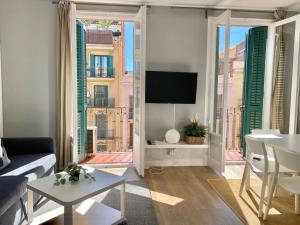 巴塞罗那2 BDR EIXAMPLE APARTMENT的带沙发、电视和窗户的客厅