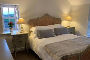 圣艾夫斯Folly Farm Cottage, Cosy, Secluded near to St Ives的一间卧室配有一张大床,桌子上放着两盏灯
