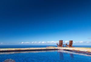科纳霍卢阿洛阿旅馆的两把椅子和一个俯瞰着大海的游泳池