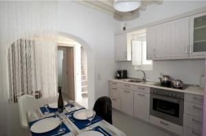 帕诺尔莫斯米科诺斯Villa ANASA private Pool & Jacuzzi 8pax at Panormos的厨房配有白色橱柜和一张带盘子的桌子