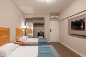 坎皮纳斯Monreale Express Glicério Campinas的酒店客房设有两张床和一台平面电视。