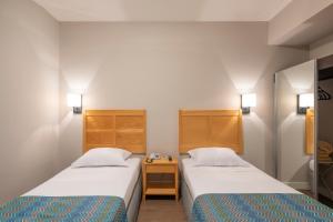 坎皮纳斯Monreale Express Glicério Campinas的一间设有两张床的房间,中间设有床头柜