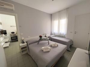里乔内Residenza Clelia Riccione的一间卧室配有两张床和一张带毛巾的桌子。