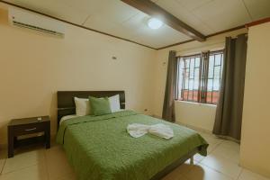 奎波斯城Quepos Inn的一间卧室设有一张绿色的床和一个窗户。
