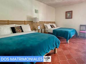 圣克里斯托瓦尔-德拉斯卡萨斯Hotel Pepe Pancho的一间卧室配有两张带蓝色床单的床和椅子