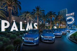 拉斯维加斯Palms Casino Resort的一排停在棕榈树前的汽车