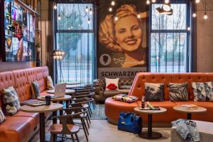 杜塞尔多夫Moxy Duesseldorf South的一间设有橙色家具和一张女士大招的招贴画的餐厅