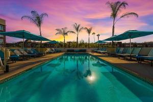 洛杉矶Courtyard by Marriott Marina del Rey的一个带椅子和遮阳伞的游泳池