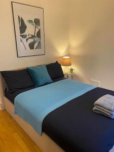 伦敦2 Bedroom Flat in Camberwell Green - Central Location with excellent connections to tourist attractions and main London airports的一间卧室配有蓝色的床和两个枕头