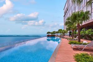 名古屋Batam Marriott Hotel Harbour Bay的一座棕榈树游泳池和一座建筑