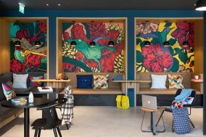 布里斯托Moxy Bristol的一间设有桌子的房间,墙上装饰着色彩缤纷的绘画作品