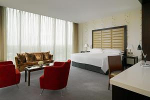 阿斯隆喜来登阿斯隆酒店的酒店客房带大床和红色椅子