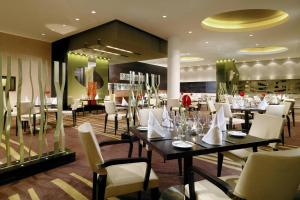 阿斯隆喜来登阿斯隆酒店的用餐室配有桌子和白色椅子
