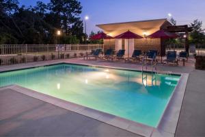 查尔斯顿TownePlace Suites by Marriott Charleston-West Ashley的夜间游泳池,配有椅子和遮阳伞