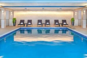 朴茨茅斯朴茨茅斯哈勃尔赛德喜来登酒店的游泳池位于酒店客房前方,配有椅子