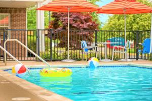韦斯特莱克Towneplace Suites by Marriott Cleveland Westlake的一个带遮阳伞和椅子的游泳池以及水中的一个球