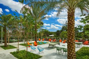 迈阿密迈阿密机场雅乐轩酒店的庭院设有桌椅,棕榈树