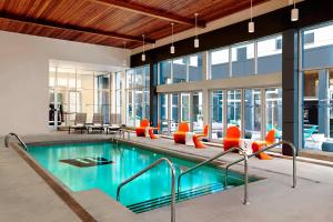 多瓦尔蒙特利尔机场雅乐轩酒店的一座带橙色椅子的游泳池和一座游泳池