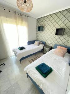 马贝拉Jolie maison à Cabopino Marbella的一间卧室配有两张床和吊灯。