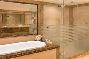科威特Sheraton Kuwait, a Luxury Collection Hotel, Kuwait City的带浴缸和玻璃淋浴间的浴室。