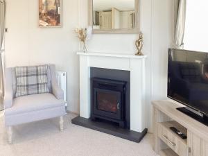 LeanachBallagan Lodge的客厅设有壁炉、椅子和电视