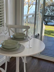 圣殿海岬水上住宿加早餐旅馆的门廊上的白色桌子,上面放有两盘和酒杯