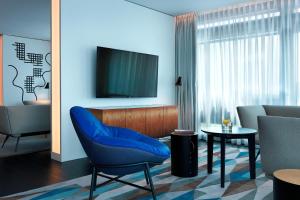 华沙Renaissance Warsaw Airport Hotel的客厅配有蓝色椅子和电视