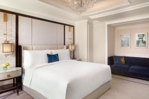 雅加达The St. Regis Jakarta的卧室配有白色的床和蓝色的沙发
