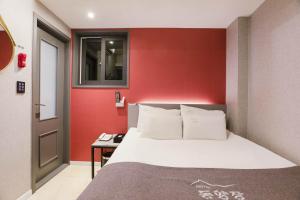 首尔Hotel dongyangjang Dongdaemun-Jongno的一间卧室设有一张床和红色的墙壁