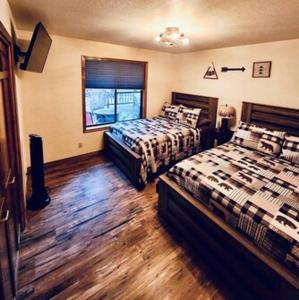 弗拉格斯塔夫Cheerful Kathys Cabin, King Bed, Hot Tub, Close to NAU, Airport & Hiking Trails!的一间卧室设有两张床和窗户。