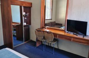 奥尔伯里西顿艾瑞斯汽车旅馆的一间卧室配有一张桌子、一台电视和两把椅子