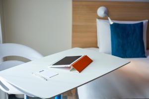 勒芒基里亚德东勒芒酒店的一张带书籍的白色桌子和一台笔记本电脑