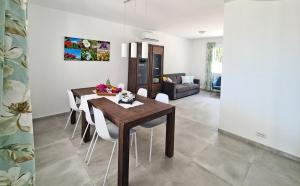 萨罗克Villa Bettina的一间带木桌和白色椅子的用餐室
