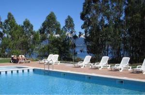 格罗韦阿贝拉斯酒店的一组白色躺椅和一个游泳池