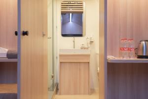 万隆Bobocabin Ranca Upas, Bandung的一间带水槽和镜子的浴室以及一台电视